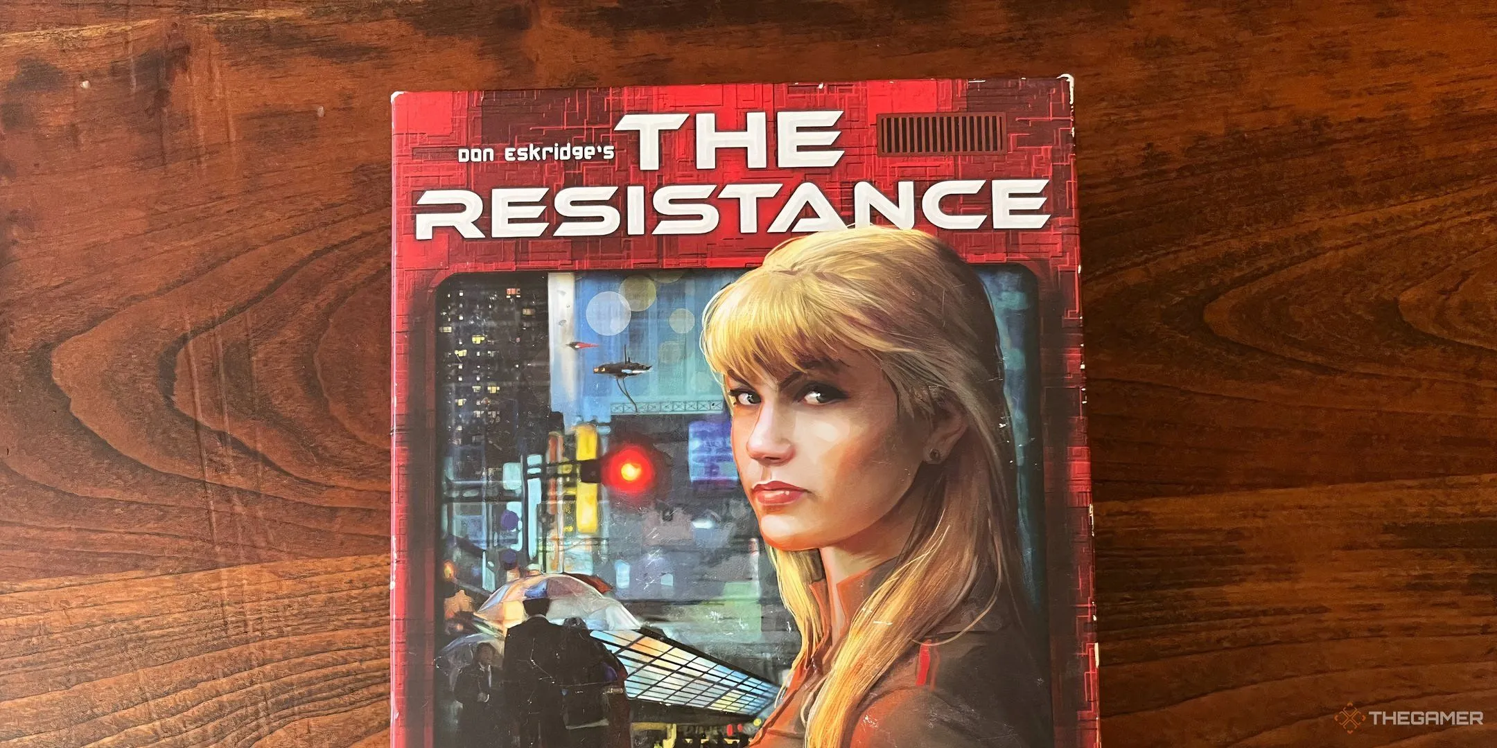 Bìa hộp board game The Resistance với hình ảnh nữ điệp viên tóc vàng, minh họa cho trò chơi phản gián và đấu trí