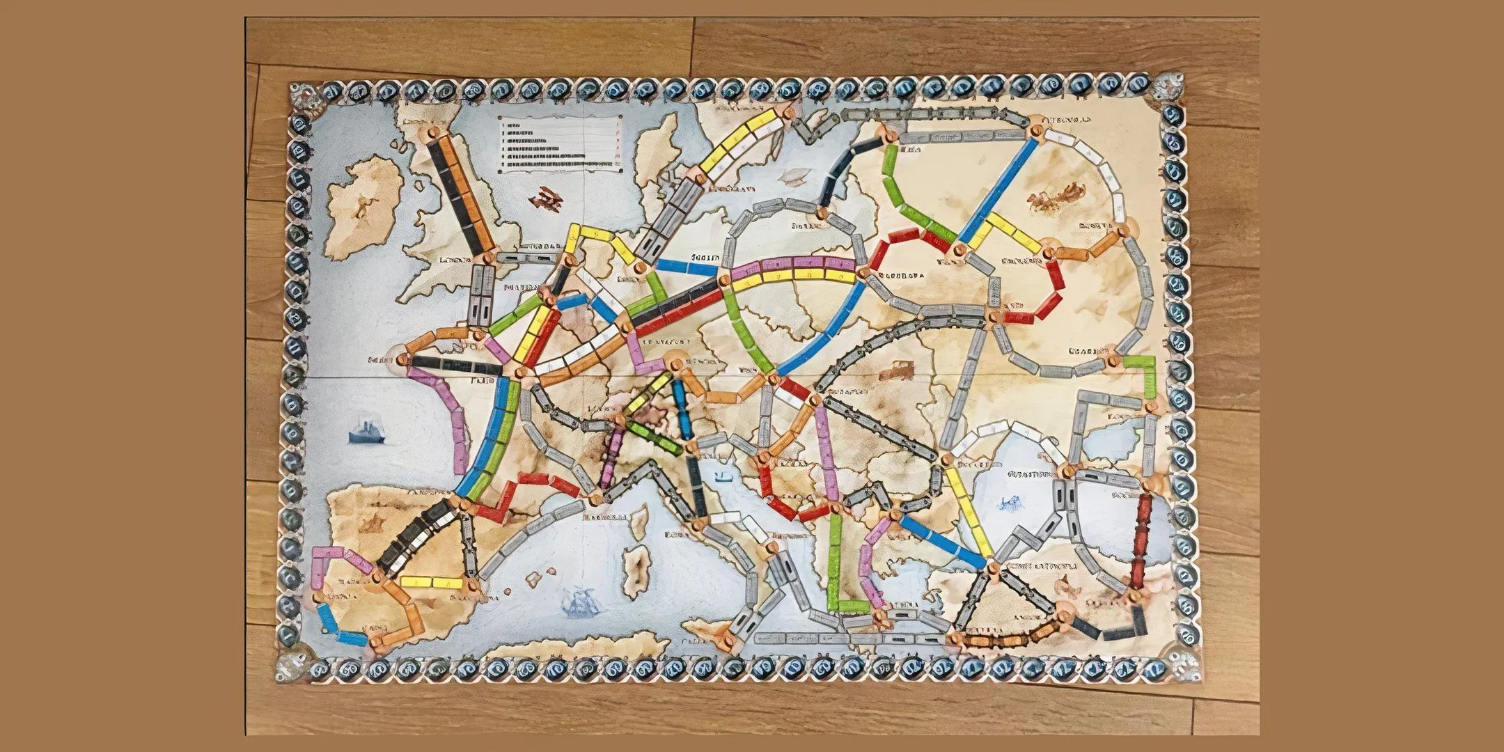 Mô tả hình ảnh: Bàn chơi của board game Ticket To Ride với các tuyến đường sắt và thẻ toa tàu được đặt trên bản đồ Bắc Mỹ.