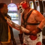 Sweet Tooth đe dọa John Doe bằng dao phay trong series Twisted Metal, biểu tượng của sự hỗn loạn hậu tận thế
